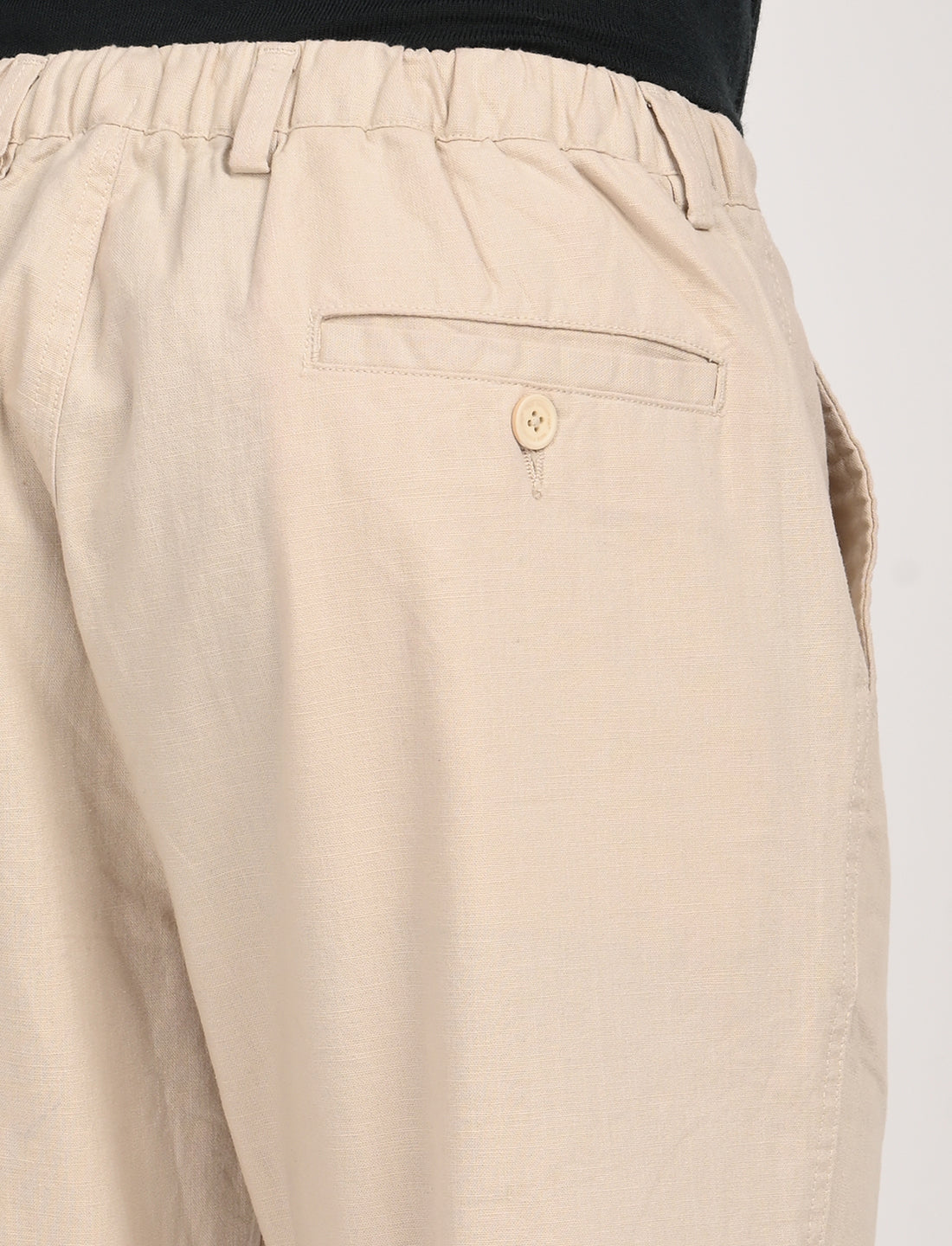 Close-up of the back pocket and waistband of cream linen blend trousers for casual and college wear.