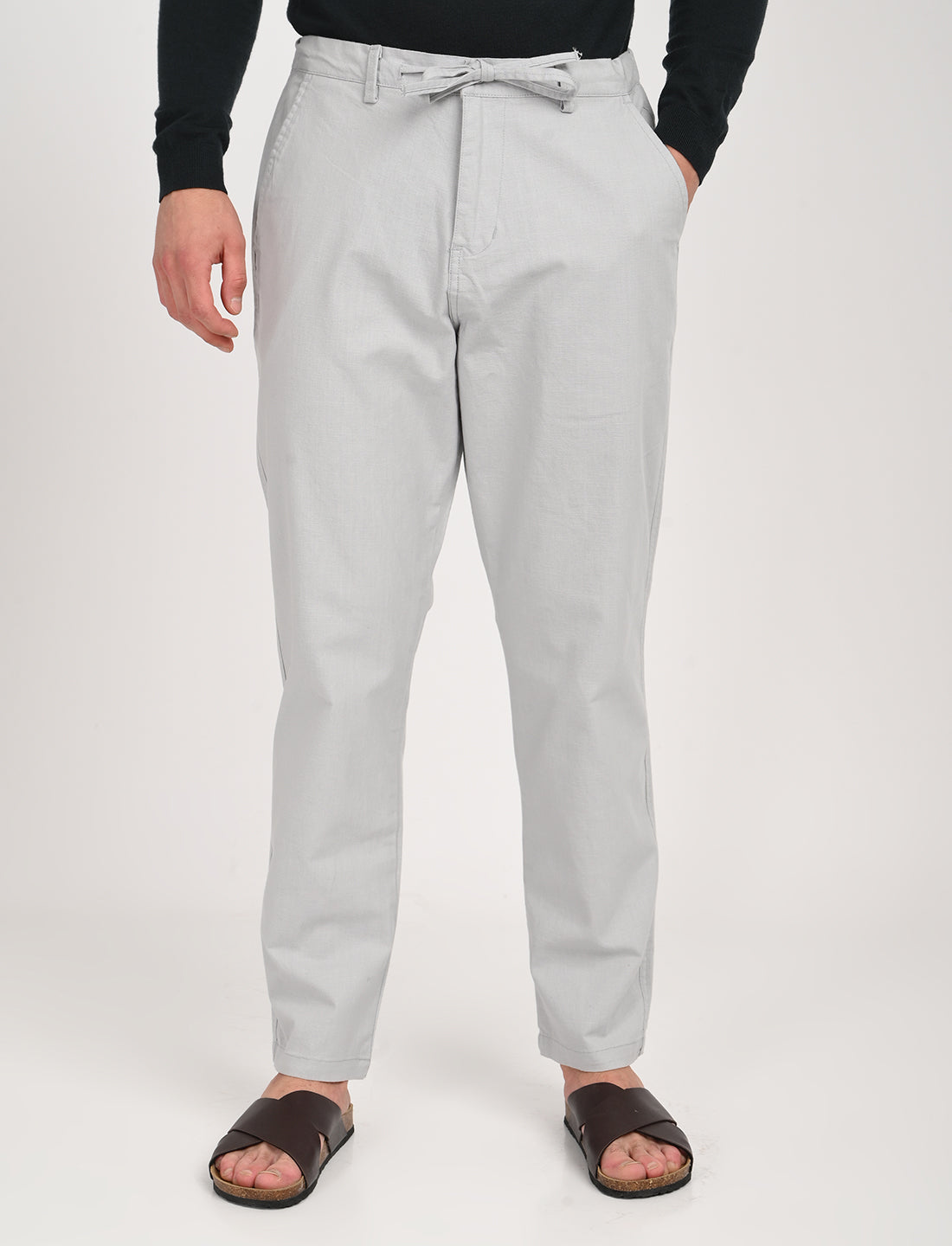 Man wearing Nova light grey linen blend trousers with a casual belt and sandals, ideal for transeasonal casual wear.