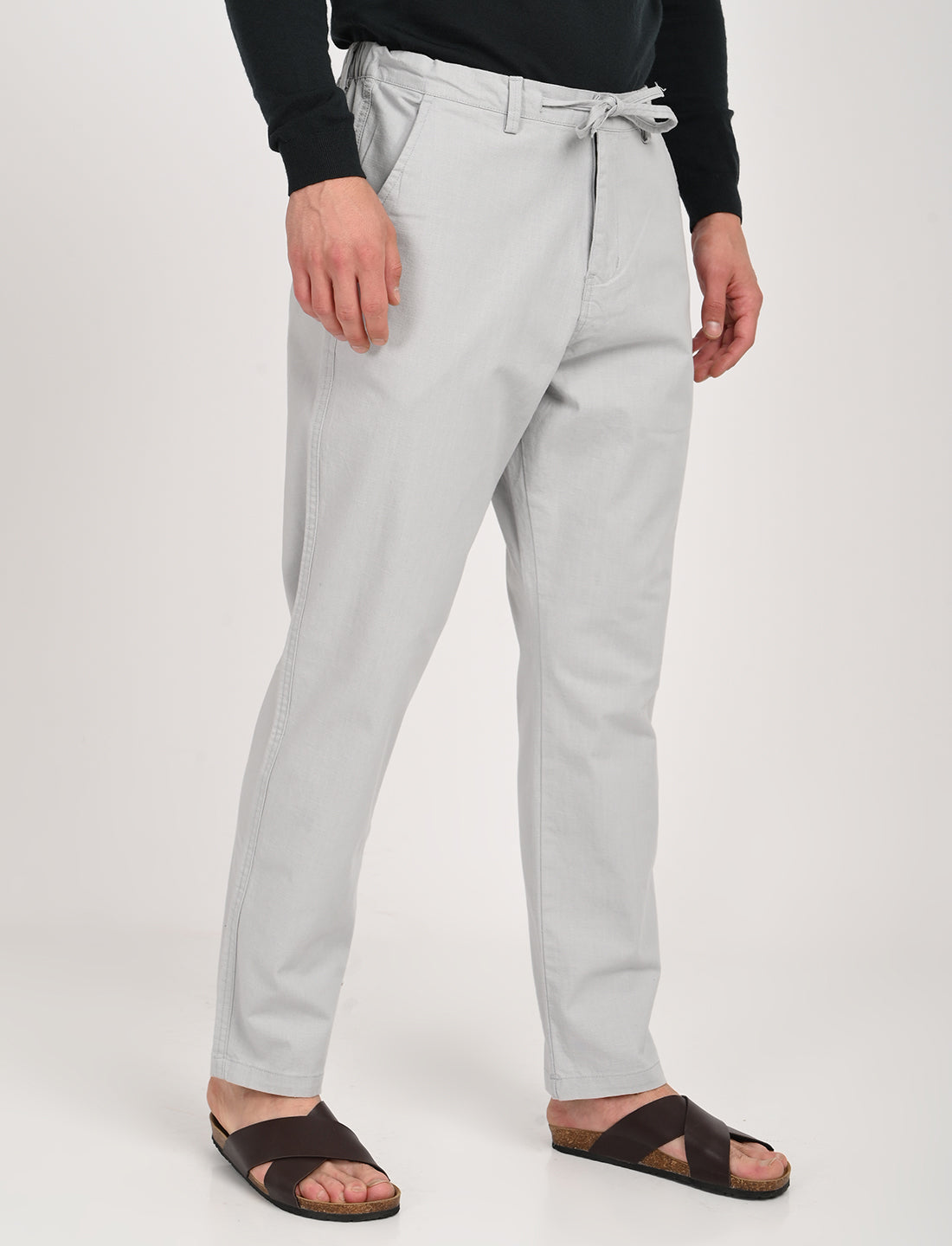 Light grey linen blend trousers with a drawstring waist, styled casually with sandals, perfect for relaxed outings.